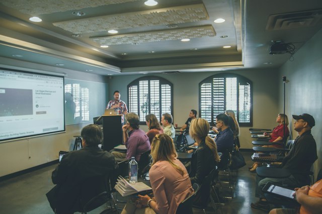 Des adultes assistent à une présentation dans une salle de formation.