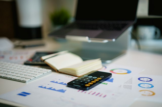 Des documents chiffrés et une calculatrice sur une table de travail.