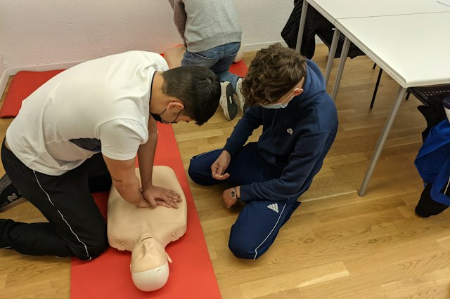 Un formateur accompagne un exercice de réanimation sur mannequin.